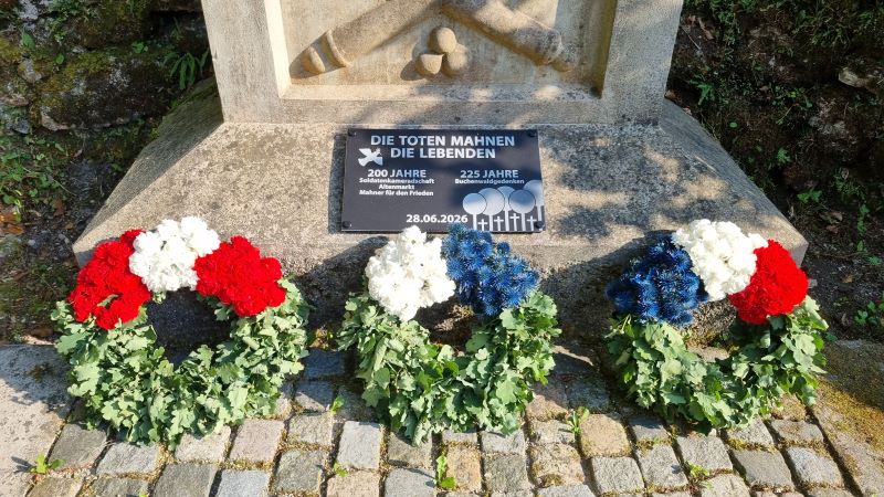 Mahnmal mit Gedenktafel und Kraenzen 20260628 180707 800px